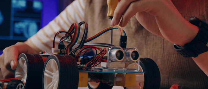 High school student using a screwdriver to assemble a robot car