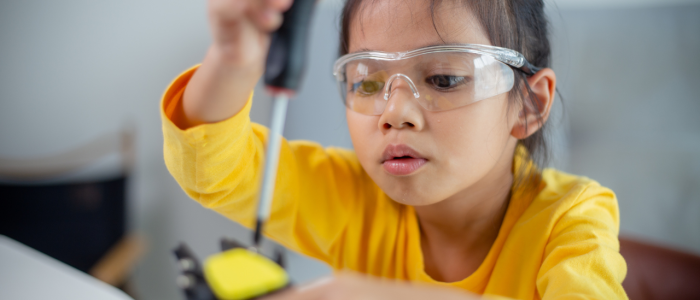 Girl using a screwdriver to adjust a part on a robot